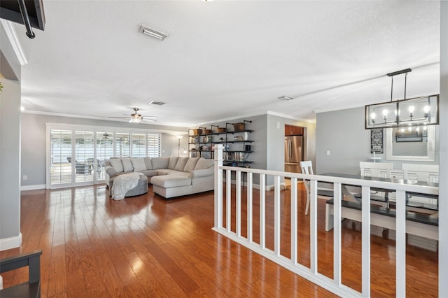 living room with a textured ceiling, ornamental molding, ceiling fan with notable chandelier, and hardwood / wood-style floors