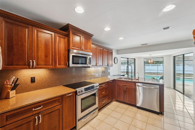 kitchen featuring light tile patterned floors, kitchen peninsula, appliances with stainless steel finishes, tasteful backsplash, and sink