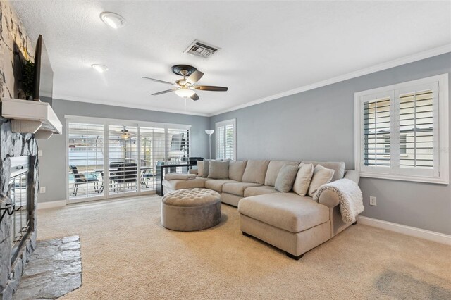 carpeted living room with ceiling fan, plenty of natural light, ornamental molding, and a fireplace