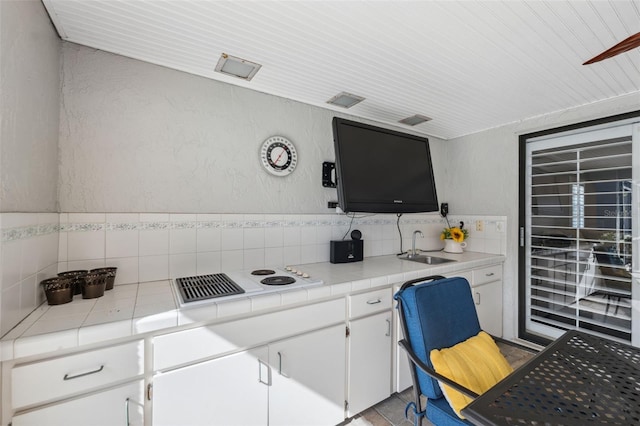 kitchen with sink, white cooktop, tile countertops, and white cabinetry