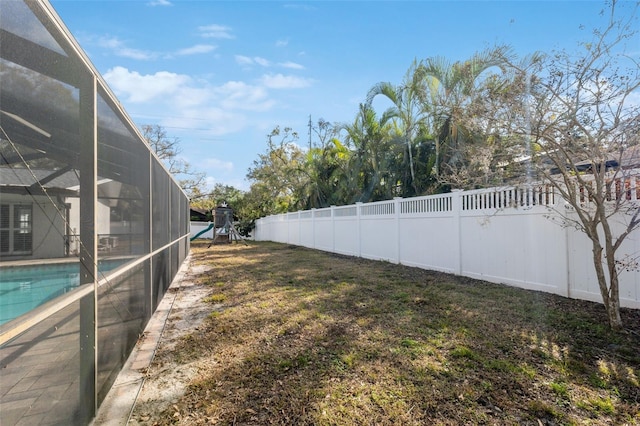 view of yard with a fenced in pool and glass enclosure