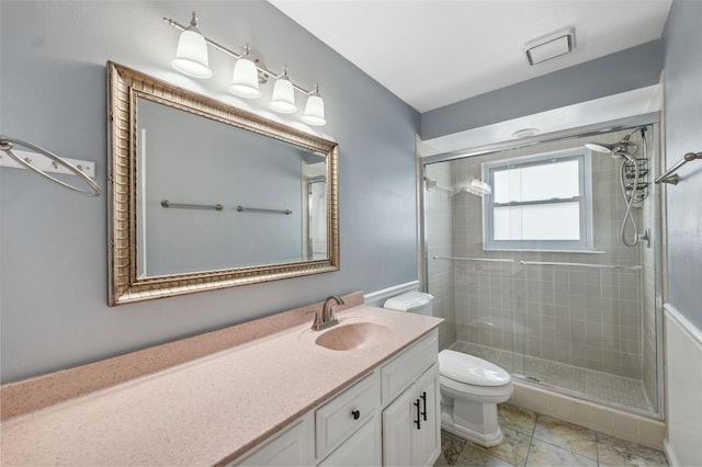 bathroom featuring toilet, tile patterned flooring, a shower with shower door, and vanity