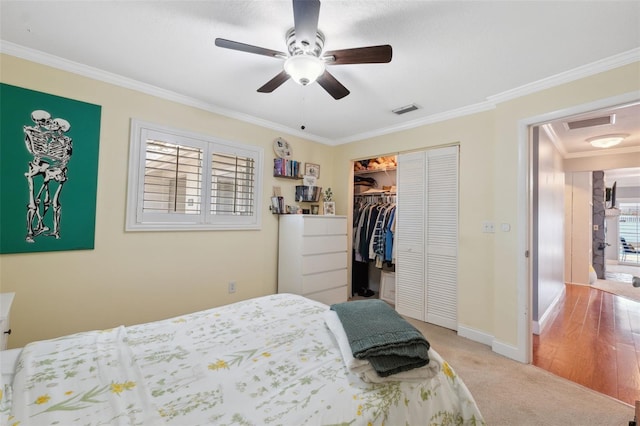 carpeted bedroom with ceiling fan, a closet, and crown molding