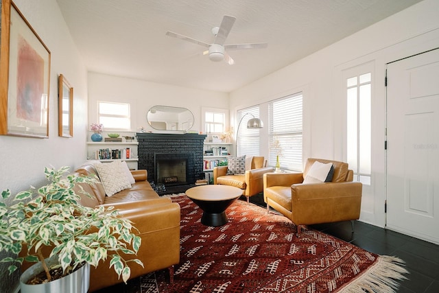 living room featuring ceiling fan, a fireplace, a wealth of natural light, and dark tile patterned flooring