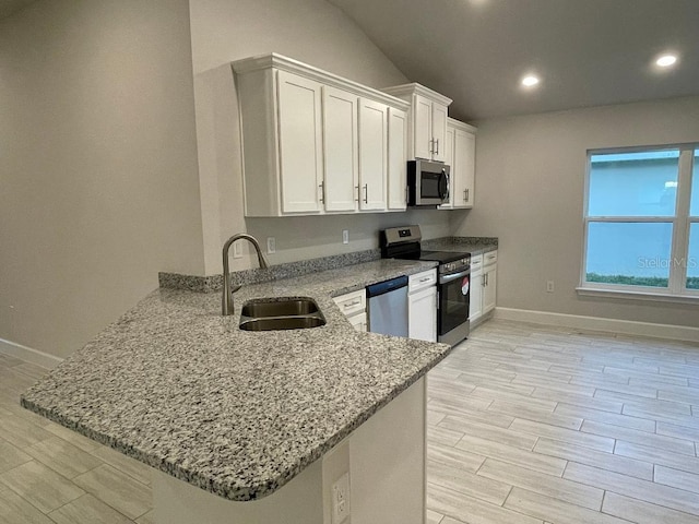 kitchen with kitchen peninsula, stainless steel appliances, light stone countertops, white cabinets, and sink