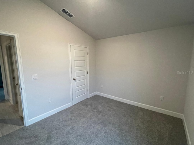 unfurnished bedroom featuring lofted ceiling and dark colored carpet