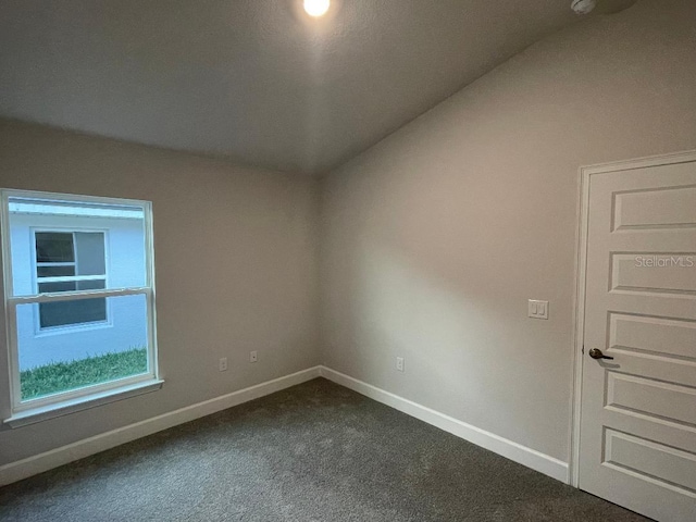 carpeted empty room with lofted ceiling