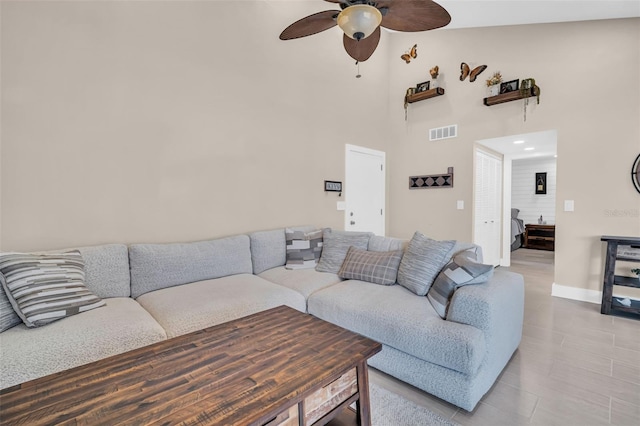 living room with ceiling fan and a high ceiling