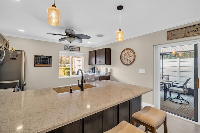 kitchen featuring decorative light fixtures, sink, stainless steel fridge, and dark brown cabinets