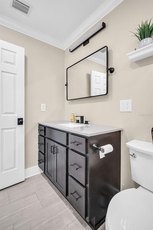 bathroom featuring toilet, vanity, and ornamental molding