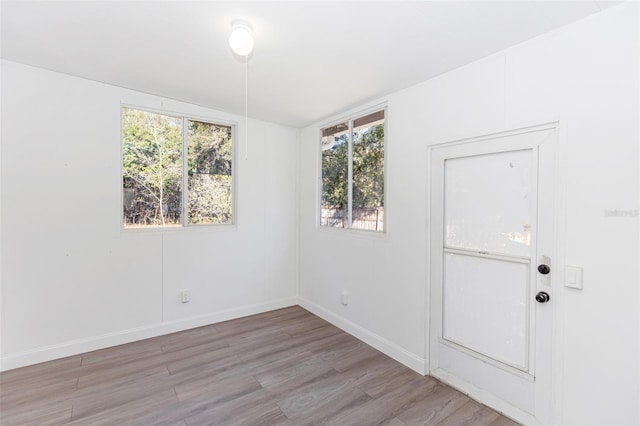 empty room featuring a wealth of natural light, light hardwood / wood-style flooring, and lofted ceiling