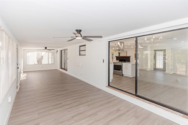 unfurnished room featuring ceiling fan with notable chandelier and light hardwood / wood-style floors