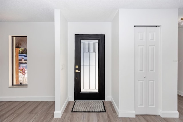 foyer with a textured ceiling and light hardwood / wood-style flooring