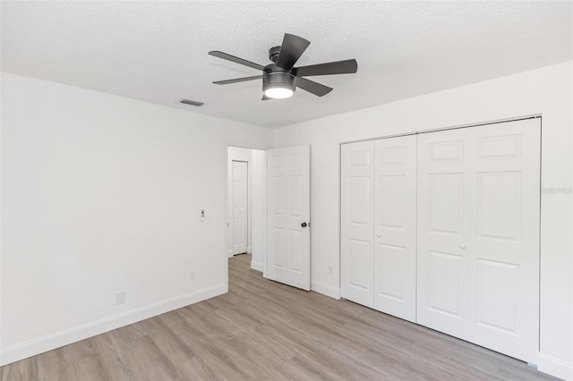 unfurnished bedroom with a textured ceiling, ceiling fan, a closet, and light hardwood / wood-style floors