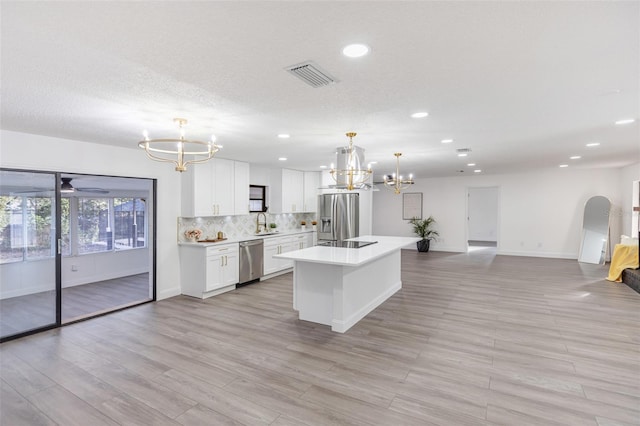 kitchen with a center island, pendant lighting, sink, white cabinetry, and stainless steel appliances