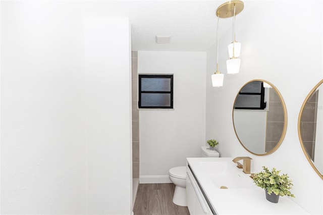 bathroom with wood-type flooring, toilet, vanity, and a textured ceiling