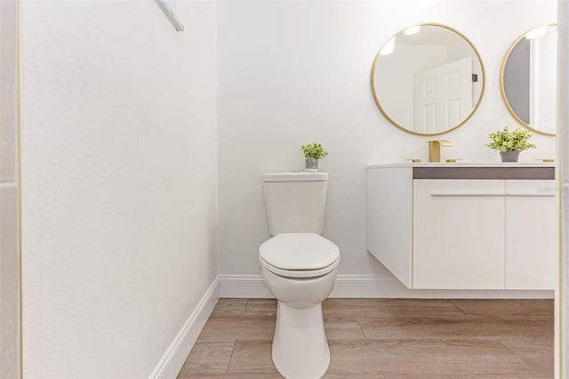 bathroom featuring wood-type flooring, toilet, and vanity