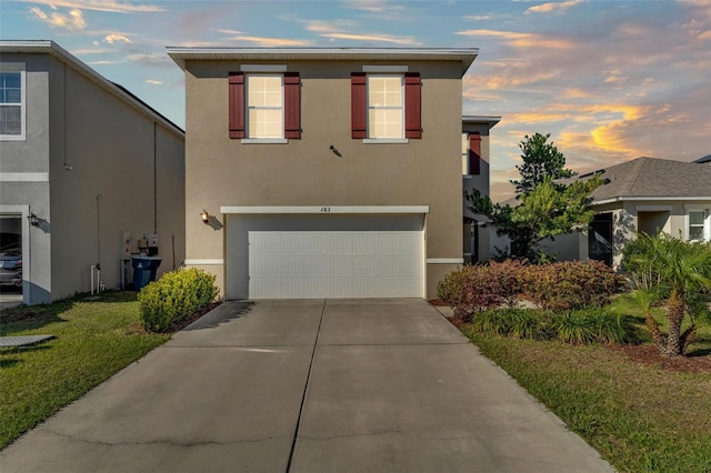 traditional home with stucco siding, concrete driveway, and an attached garage