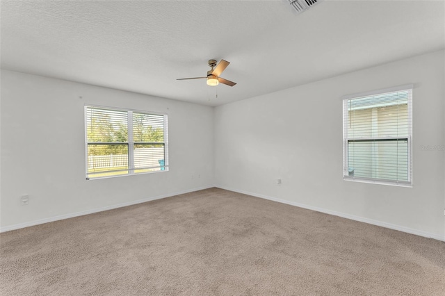 carpeted spare room with visible vents, baseboards, a textured ceiling, and ceiling fan