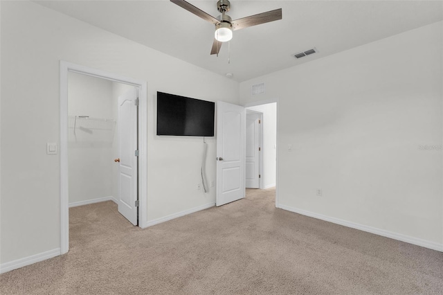 unfurnished bedroom with visible vents, light colored carpet, a walk in closet, and baseboards