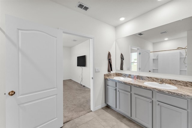 full bathroom featuring a sink, visible vents, double vanity, and tile patterned floors