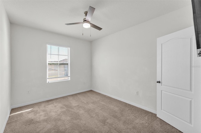 carpeted spare room featuring baseboards and ceiling fan