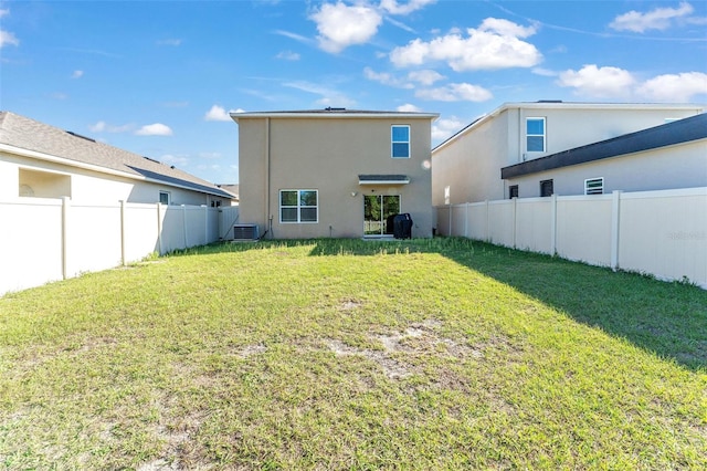 back of property with central AC unit, a lawn, a fenced backyard, and stucco siding