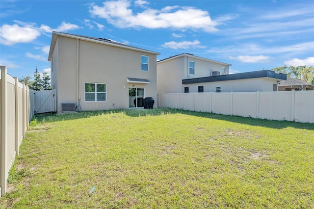 rear view of house featuring central AC unit, a yard, a fenced backyard, and stucco siding