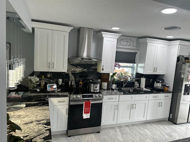 kitchen with appliances with stainless steel finishes, white cabinetry, sink, dark stone countertops, and wall chimney range hood