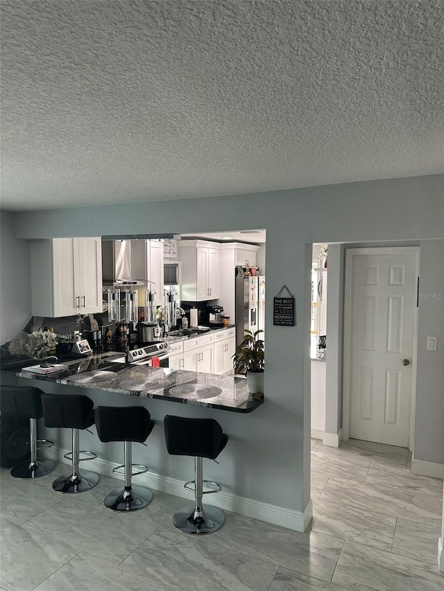 kitchen featuring stainless steel fridge with ice dispenser, white cabinets, dark stone counters, and kitchen peninsula