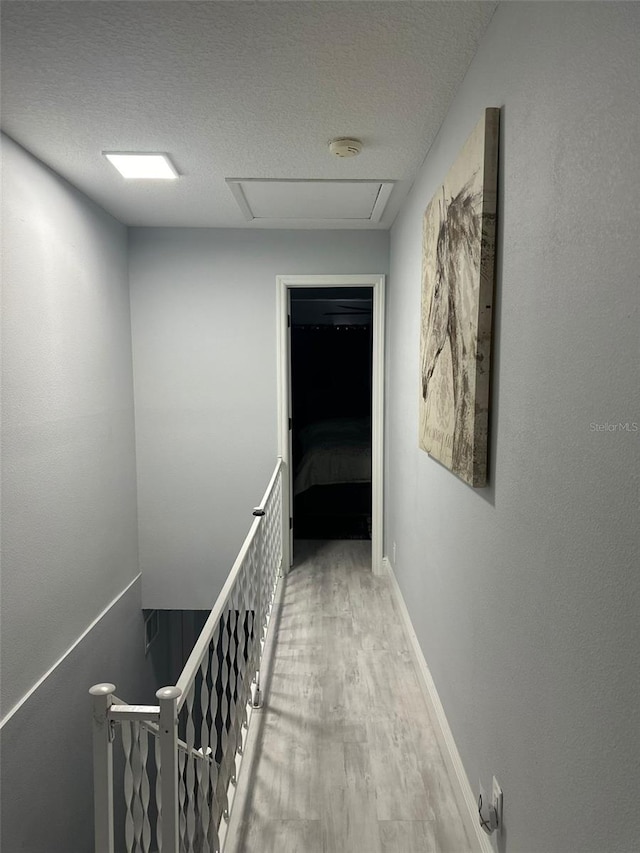 hall featuring a textured ceiling and light wood-type flooring