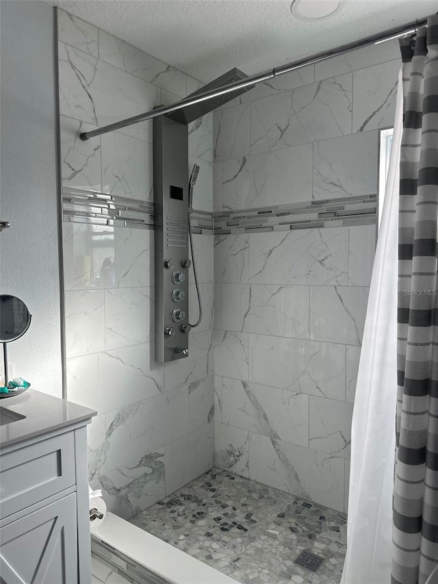 bathroom with walk in shower, vanity, and a textured ceiling