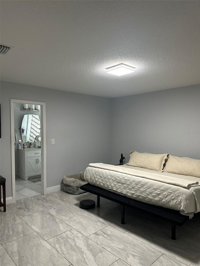 bedroom with ensuite bathroom and a textured ceiling