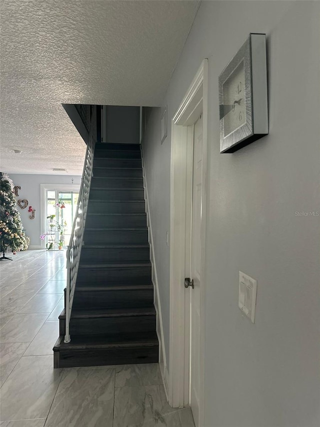 stairs with a textured ceiling