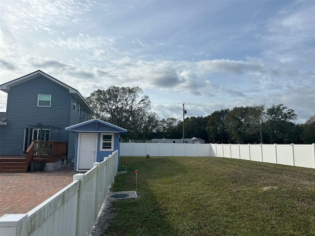 view of yard featuring a storage shed, a deck, and a patio area