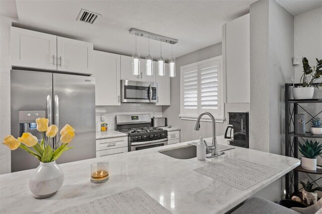 kitchen with stainless steel appliances, white cabinetry, a breakfast bar, and sink