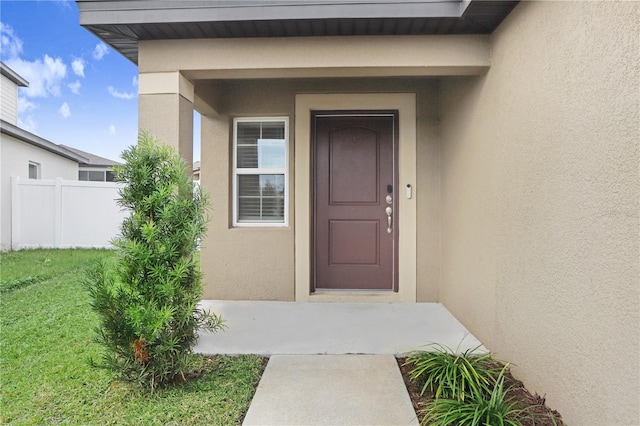 view of exterior entry featuring a lawn