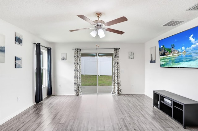 interior space featuring light wood-type flooring, ceiling fan, and plenty of natural light