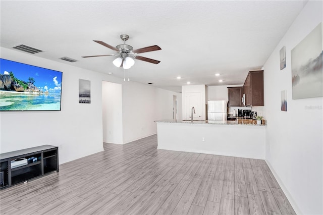 living room with ceiling fan, sink, and light wood-type flooring