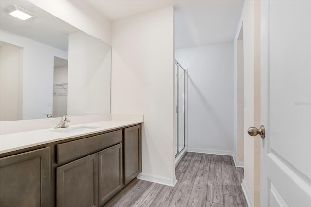 bathroom with an enclosed shower, vanity, and wood-type flooring