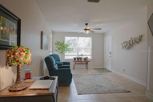 tiled living room with a textured ceiling and ceiling fan