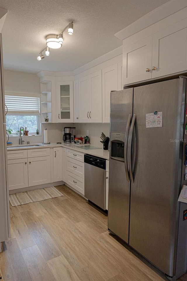 kitchen with appliances with stainless steel finishes, light hardwood / wood-style floors, sink, and white cabinets