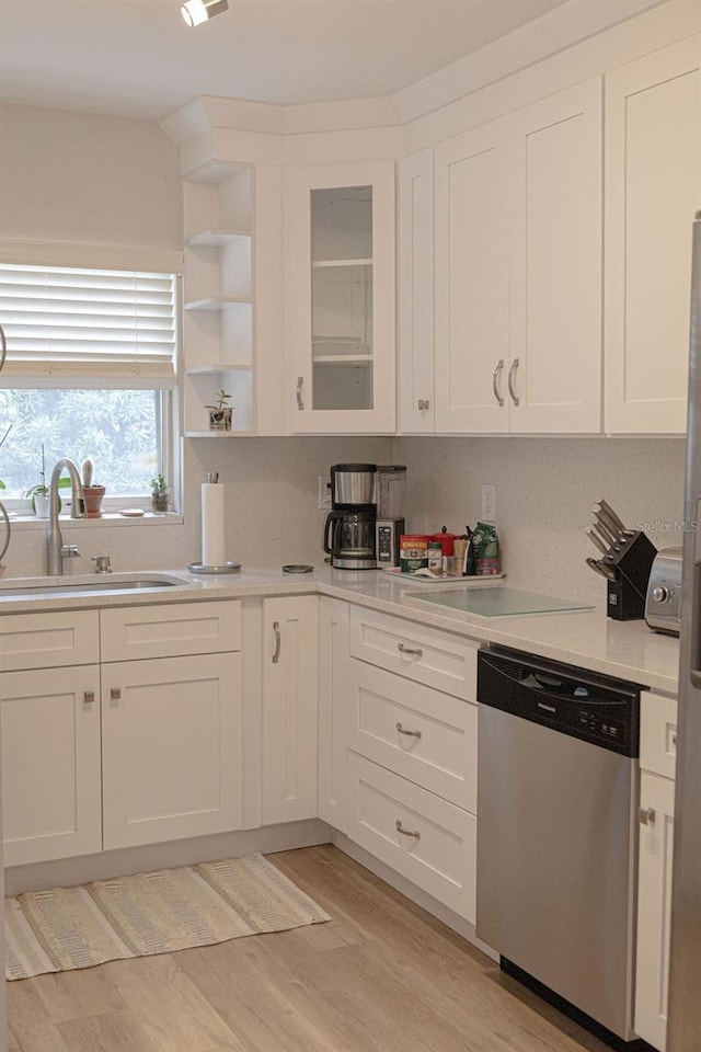 kitchen featuring stainless steel dishwasher, light hardwood / wood-style floors, sink, and white cabinets