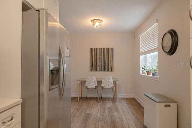 interior space with light hardwood / wood-style flooring, white cabinetry, and stainless steel fridge