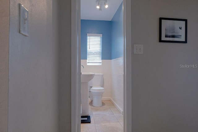 bathroom with tile patterned floors, toilet, and tile walls