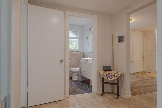 hall featuring light tile patterned flooring and tile walls