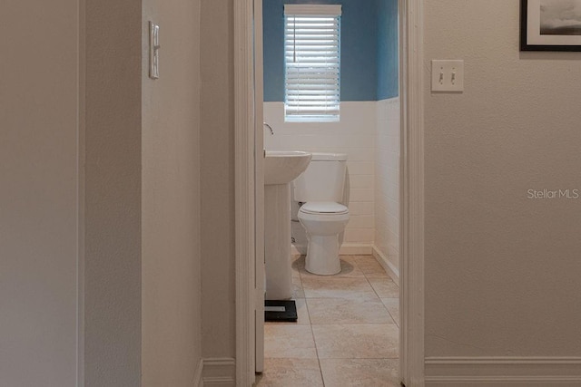 bathroom featuring tile walls, tile patterned floors, and toilet