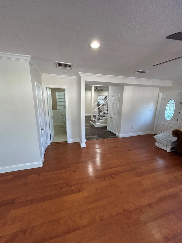 spare room featuring crown molding, dark hardwood / wood-style floors, and a textured ceiling