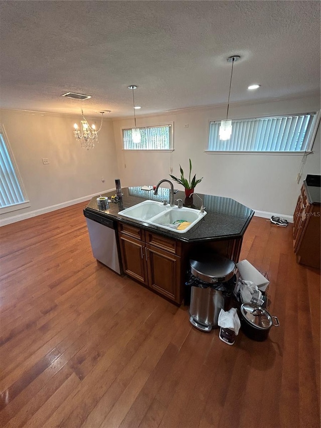 kitchen with a textured ceiling, sink, hardwood / wood-style flooring, stainless steel dishwasher, and a center island with sink