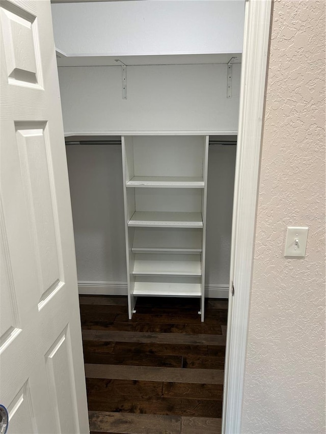 walk in closet with dark wood-type flooring